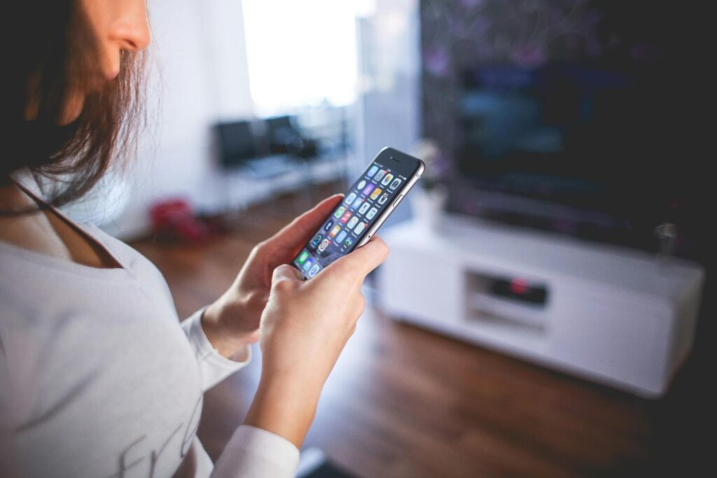 seorang wanita memegang telefonnya semasa berada di rumah