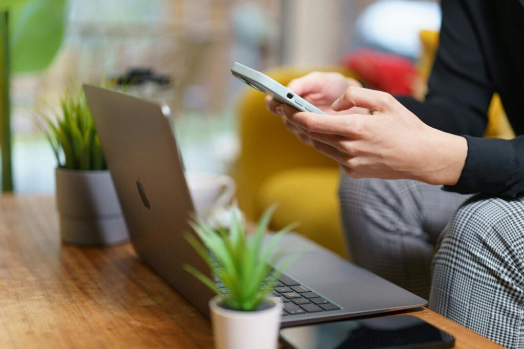 seseorang menggunakan ponsel dan laptop