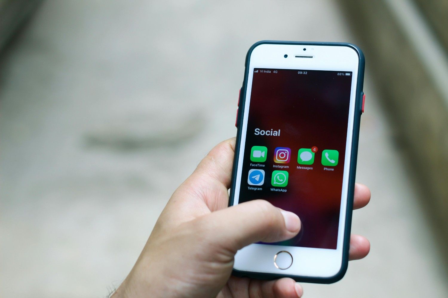 a person holding a white cellphone with app icons on the screen